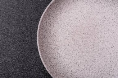 Empty ceramic round plate on dark textured concrete background. Cutlery, preparation for dinner