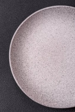 Empty ceramic round plate on dark textured concrete background. Cutlery, preparation for dinner