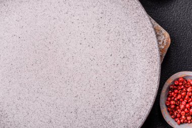 Empty ceramic round plate on dark textured concrete background. Cutlery, preparation for dinner