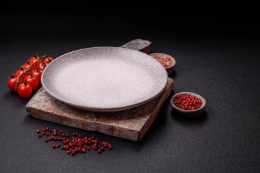 Empty ceramic round plate on dark textured concrete background. Cutlery, preparation for dinner