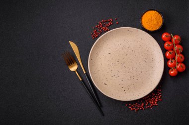 Empty ceramic round plate on dark textured concrete background. Cutlery, preparation for dinner