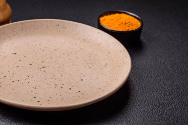 Empty ceramic round plate on dark textured concrete background. Cutlery, preparation for dinner