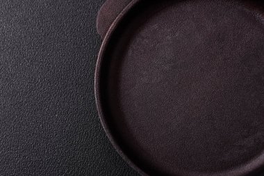 Empty ceramic round plate on dark textured concrete background. Cutlery, preparation for dinner
