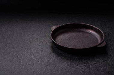 Empty ceramic round plate on dark textured concrete background. Cutlery, preparation for dinner