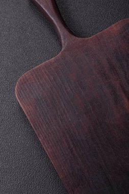 Boş ahşap kesme tahtası. Baharatlar, tuz ve otlar koyu beton arka planda.