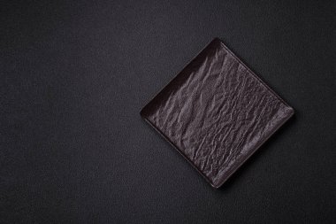 Empty ceramic round plate on dark textured concrete background. Cutlery, preparation for dinner
