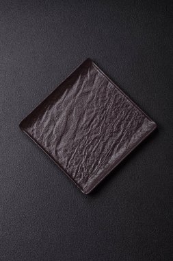 Empty ceramic round plate on dark textured concrete background. Cutlery, preparation for dinner