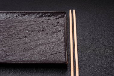 Empty ceramic round plate on dark textured concrete background. Cutlery, preparation for dinner