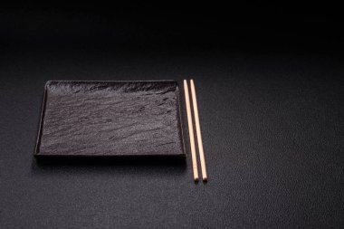 Empty ceramic round plate on dark textured concrete background. Cutlery, preparation for dinner
