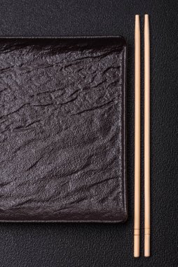 Empty ceramic round plate on dark textured concrete background. Cutlery, preparation for dinner