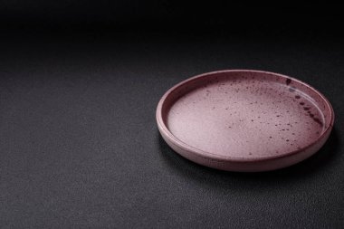 Empty ceramic round plate on dark textured concrete background. Cutlery, preparation for dinner