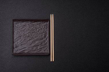 Empty ceramic round plate on dark textured concrete background. Cutlery, preparation for dinner