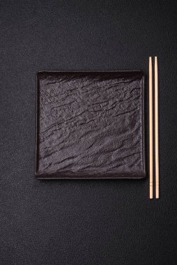 Empty ceramic round plate on dark textured concrete background. Cutlery, preparation for dinner