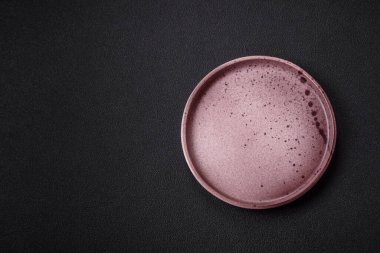 Empty ceramic round plate on dark textured concrete background. Cutlery, preparation for dinner