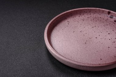 Empty ceramic round plate on dark textured concrete background. Cutlery, preparation for dinner