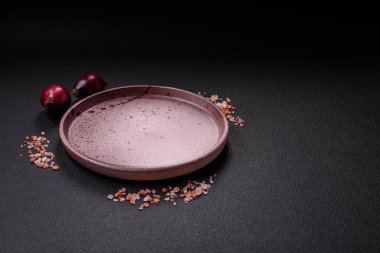 Empty ceramic round plate on dark textured concrete background. Cutlery, preparation for dinner