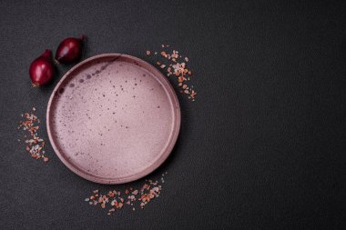Empty ceramic round plate on dark textured concrete background. Cutlery, preparation for dinner