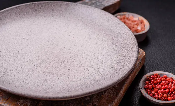Empty ceramic round plate on dark textured concrete background. Cutlery, preparation for dinner