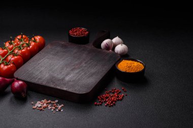 Koyu beton arka planda ev biberi, tuz, baharat ve bitkiler pişirmek için gerekli malzemeler