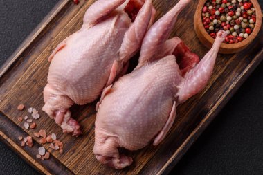 Tuzlu, baharatlı ve otlu tam çiğ bıldırcın. Koyu beton arka planda pişirmek için hazırlanmış.