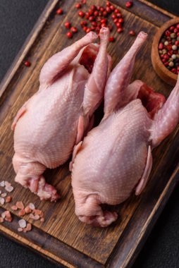 Tuzlu, baharatlı ve otlu tam çiğ bıldırcın. Koyu beton arka planda pişirmek için hazırlanmış.