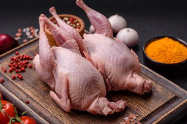 Tuzlu, baharatlı ve otlu tam çiğ bıldırcın. Koyu beton arka planda pişirmek için hazırlanmış.