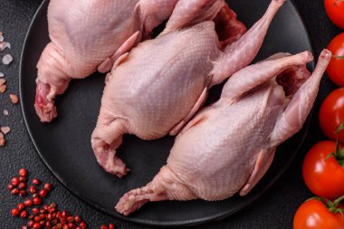 Tuzlu, baharatlı ve otlu tam çiğ bıldırcın. Koyu beton arka planda pişirmek için hazırlanmış.