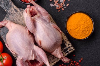 Tuzlu, baharatlı ve otlu tam çiğ bıldırcın. Koyu beton arka planda pişirmek için hazırlanmış.