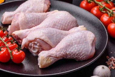 Tuzlu, baharatlı ve otlu çiğ tavuk budu. Koyu beton arka planda pişirmeye hazır.