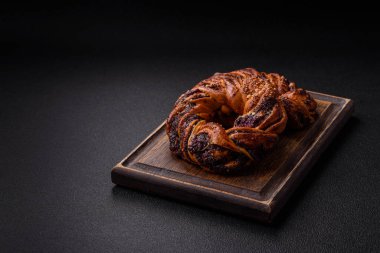 Lezzetli taze haşlanmış çörek, haşhaş tohumları ve koyu beton arka planda halka şeklinde böğürtlenler.