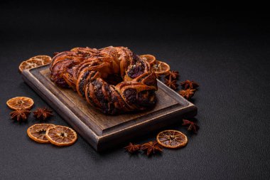 Lezzetli taze haşlanmış çörek, haşhaş tohumları ve koyu beton arka planda halka şeklinde böğürtlenler.