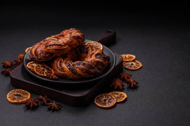 Lezzetli taze haşlanmış çörek, haşhaş tohumları ve koyu beton arka planda halka şeklinde böğürtlenler.