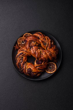 Lezzetli taze haşlanmış çörek, haşhaş tohumları ve koyu beton arka planda halka şeklinde böğürtlenler.