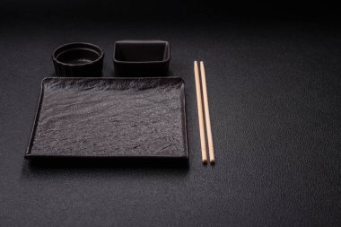 Empty ceramic round plate on dark textured concrete background. Cutlery, preparation for dinner