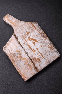 Empty wooden cutting board on dark textured concrete background. Cutlery, preparation for dinner