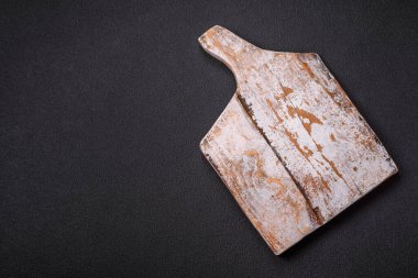 Empty wooden cutting board on dark textured concrete background. Cutlery, preparation for dinner