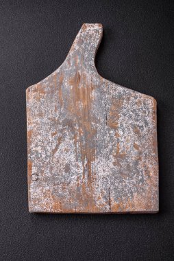 Empty wooden cutting board on dark textured concrete background. Cutlery, preparation for dinner