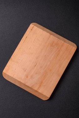 Empty wooden cutting board on dark textured concrete background. Cutlery, preparation for dinner