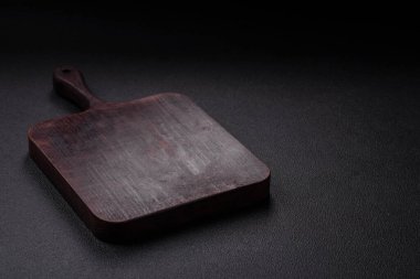 Empty wooden cutting board on dark textured concrete background. Cutlery, preparation for dinner