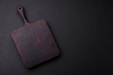 Empty wooden cutting board on dark textured concrete background. Cutlery, preparation for dinner
