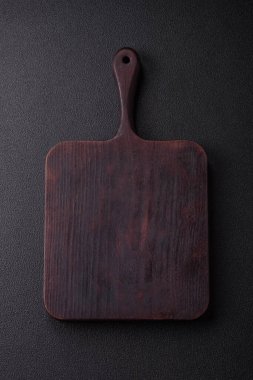 Empty wooden cutting board on dark textured concrete background. Cutlery, preparation for dinner