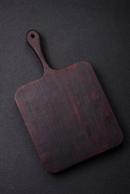 Empty wooden cutting board on dark textured concrete background. Cutlery, preparation for dinner