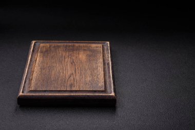 Empty wooden cutting board on dark textured concrete background. Cutlery, preparation for dinner