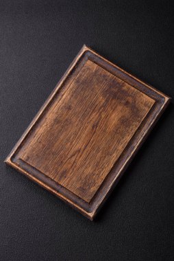 Empty wooden cutting board on dark textured concrete background. Cutlery, preparation for dinner