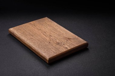 Empty wooden cutting board on dark textured concrete background. Cutlery, preparation for dinner