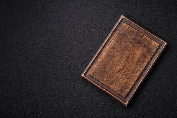 Empty wooden cutting board on dark textured concrete background. Cutlery, preparation for dinner