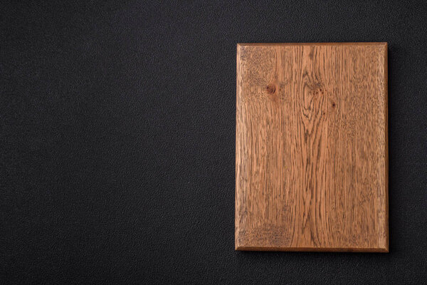 Empty wooden cutting board on dark textured concrete background. Cutlery, preparation for dinner