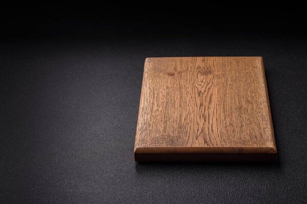 Empty wooden cutting board on dark textured concrete background. Cutlery, preparation for dinner
