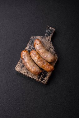 Koyu beton arka planda fırında tavuk ya da domuz sosisi, tuz, baharat ve otlar.
