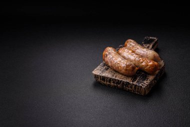 Koyu beton arka planda fırında tavuk ya da domuz sosisi, tuz, baharat ve otlar.